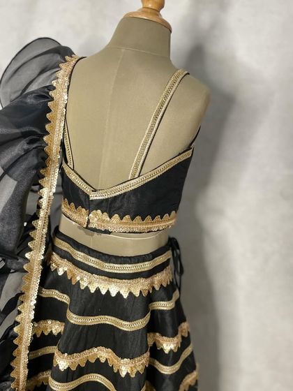 The back view of the black and gold sangeet lehenga, showing the simple, elegant straps of the choli.
