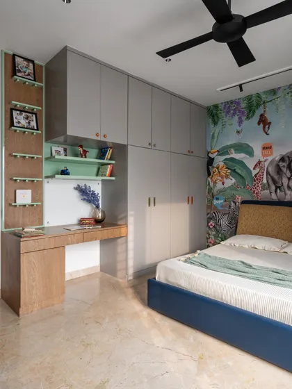 In this jungle-themed kid's room, we designed a custom study nook integrated with the wardrobe. The space is functional, with ample storage and open shelving for books and decor.