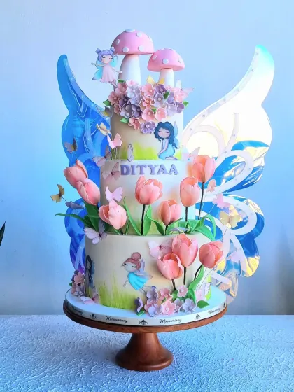 This is one of my special creations, a three-tier enchanted garden cake with mechanical moving butterfly wings. The cake is adorned with delicate sugar flowers, hand-painted details, and whimsical fairies, making it a truly interactive and magical centerpiece for a special birthday.