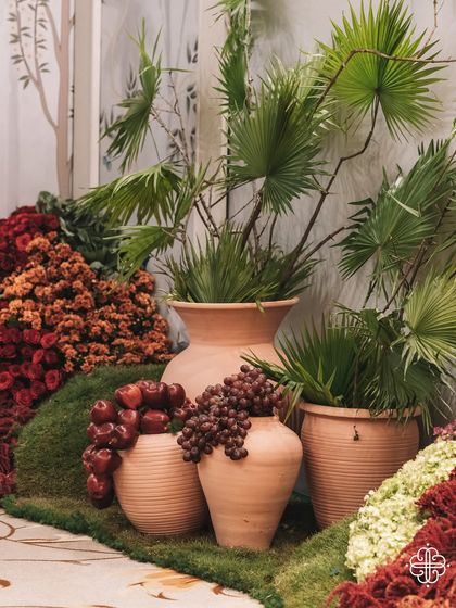 Earthen pots filled with palm leaves and grapes, part of the symbolic decor for the 'Orchard of Life' naming ceremony.