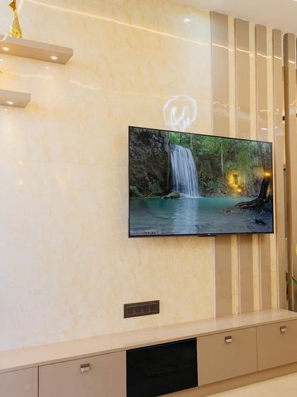 The TV unit in the Eldeco Aamantran project, with a beige console, marble-finish back panel, and fluted side panels.