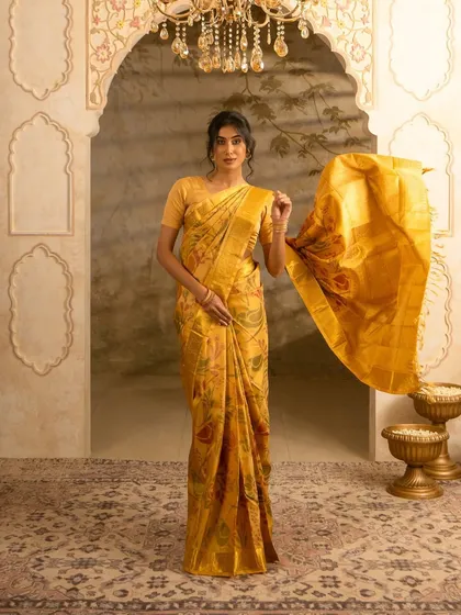 A dynamic shot of a model holding out the pallu of her yellow silk saree, showing its movement and flow. This action adds life to the garment and is great for lookbooks.