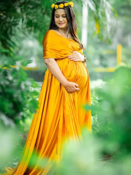 A serene portrait in a lush, green setting. The vibrant yellow gown contrasts beautifully with the natural background, creating a photo that is full of life.