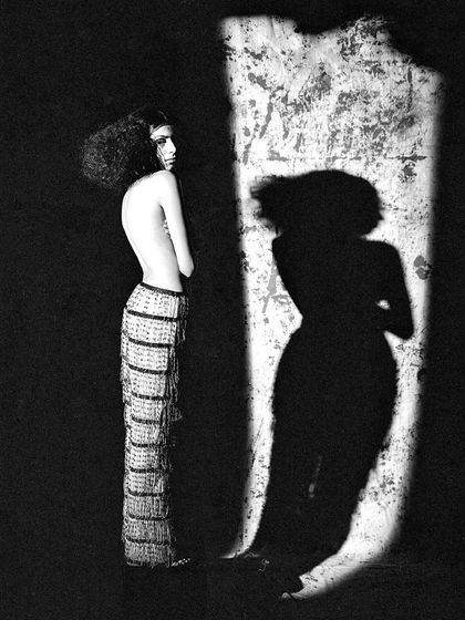 Another artistic shot playing with shadows. The model's pose is sculptural, and the strong contrast between light and dark creates a visually arresting image.