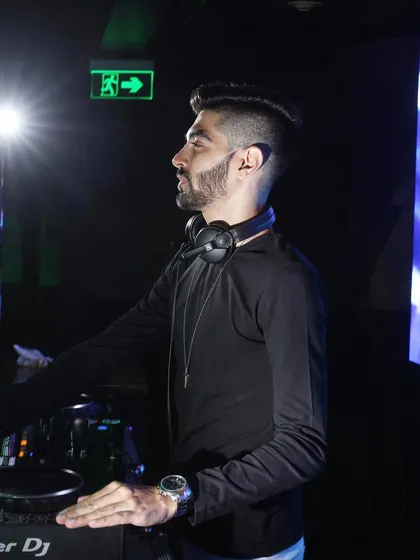A profile shot of me at the Pioneer DJ console, with headphones around my neck, ready for the next transition. This highlights the professional-grade equipment I use for all my gigs.