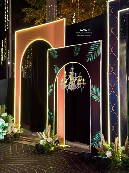 A unique entrance design for a Sangeet, with layered arches featuring tropical prints, chandeliers, and neon outlines.