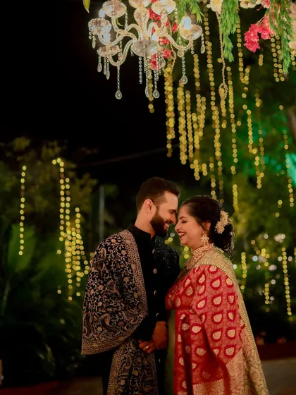 Standing under a beautiful chandelier and fairy lights, the couple shares a happy, intimate moment, their smiles lighting up the night.