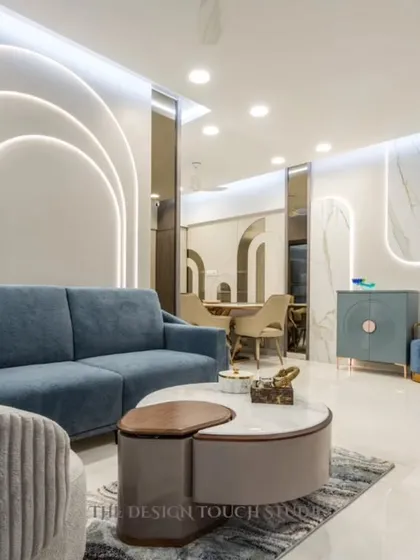 A full view of the living room, showcasing the interplay of curved wall panels, modern furniture, and sophisticated lighting. The design creates a space that is both visually interesting and incredibly comfortable.