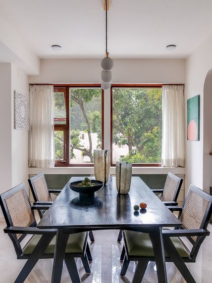 A front-on view of the dining table, with the large window and its lush green view serving as the perfect natural backdrop.