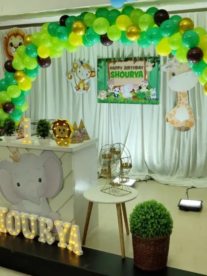 A side view of the jungle safari birthday setup. This shows the custom elephant-themed counter, light-up name, and how the balloon arch creates a perfect frame for the stage.