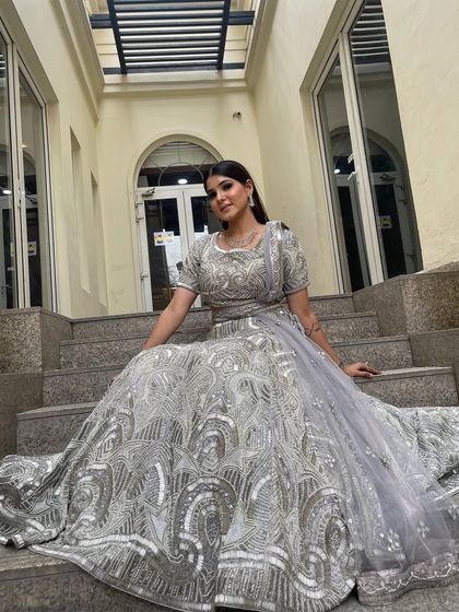 A stunning silver-grey lehenga with intricate sequin and mirror work. This is a perfect outfit for a sundowner event or an evening reception, offering a sophisticated and glamorous look.