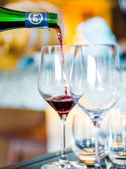 A glass of red wine being poured, a perfect accompaniment to a celebratory meal. We offer a wide selection of beverages to complement our festive menus.