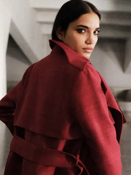 A close-up from the back, focusing on the collar and structure of a deep red coat. The angle highlights the garment's tailoring and design.