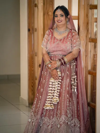 A classic full-length portrait of the bride in her beautiful pink lehenga, ready for her big day. Her calm smile radiates grace.