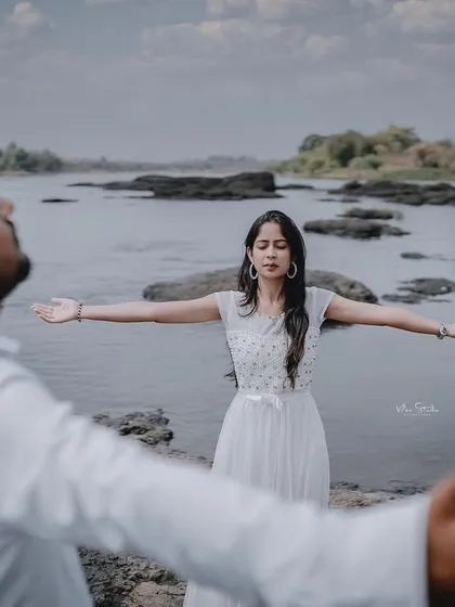 A creative shot inspired by a famous movie pose. This photo is fun, dramatic, and shows the couple's free-spirited nature against a beautiful riverside backdrop.