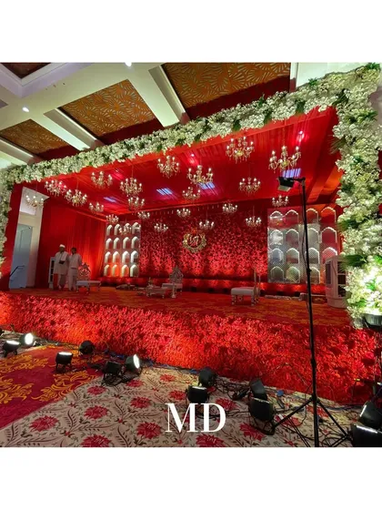 A side view of the opulent red-themed engagement stage. The stage is elevated and covered in red flowers, framed by a border of white blooms, making it a stunning focal point.