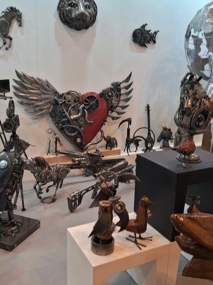 A wide view of the Momas Art Gallery booth, featuring a winged heart sculpture and other mechanical creations.