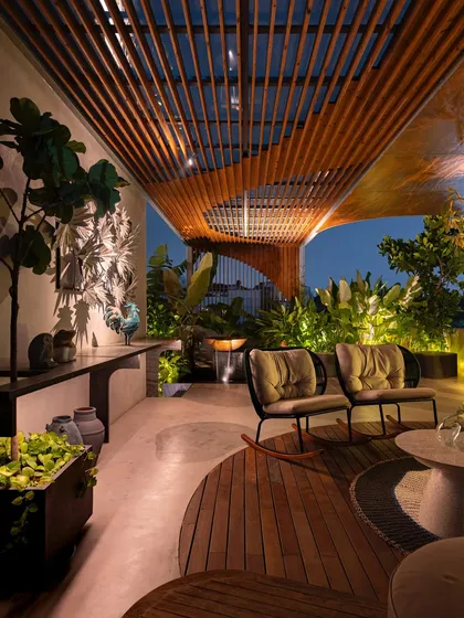 A rooftop garden comes alive at dusk. Thoughtful landscape lighting highlights the textures of the plants and the warmth of the wooden pergola, extending the usability of the space and creating a magical evening ambiance.