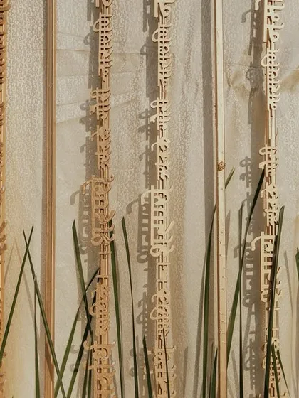 A unique backdrop detail from Aashvi and Akash's wedding, featuring hanging wooden panels with Sanskrit verses, adding a deeply personal and spiritual touch to the decor.