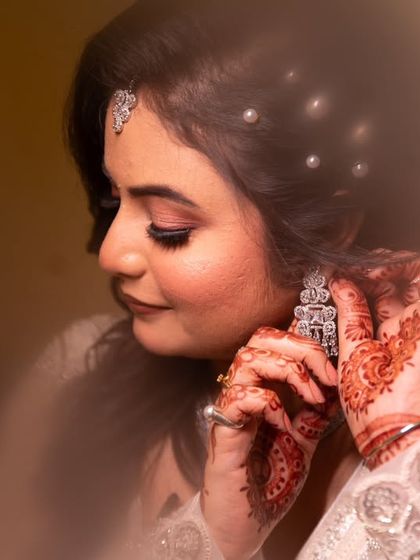 Adorning herself with dreams. This soft-focus shot captures a bride's quiet moment, highlighting the intricate mehndi and the sparkle of her earrings.