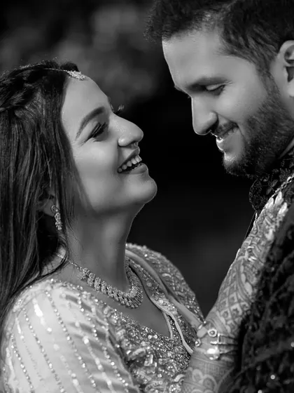A timeless black and white portrait capturing a moment of shared laughter and intimacy. This is a classic example of a candid wedding photograph.