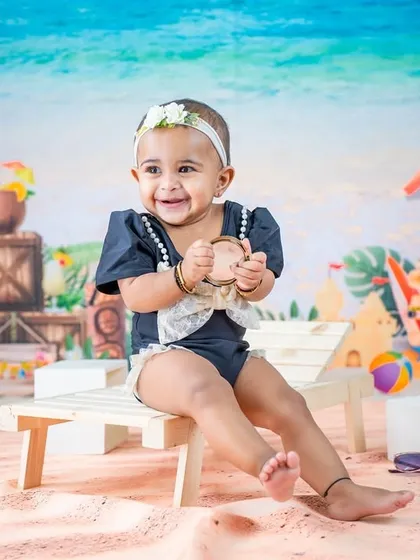 A happy smile from the beach chair. The colorful, illustrated backdrop and props make this a fun and vibrant summer scene.