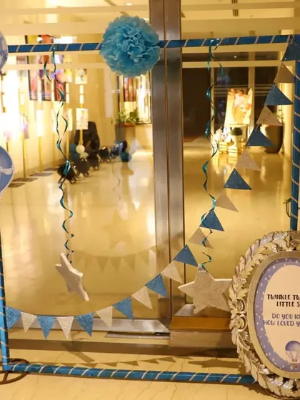 A custom photo frame prop for guests to take pictures with. The frame is decorated with hot air balloon cutouts, stars, and a pennant banner, all in the party's color scheme.