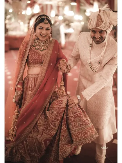 It's the unposed moments that often tell the best stories. Here, the groom playfully helps his bride with her lehenga as they walk, sharing a laugh.