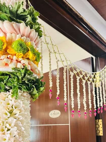 Detailing on a door frame for a housewarming ceremony. We teach you how to combine different flowers and materials to create beautiful, welcoming entrances for any traditional event.