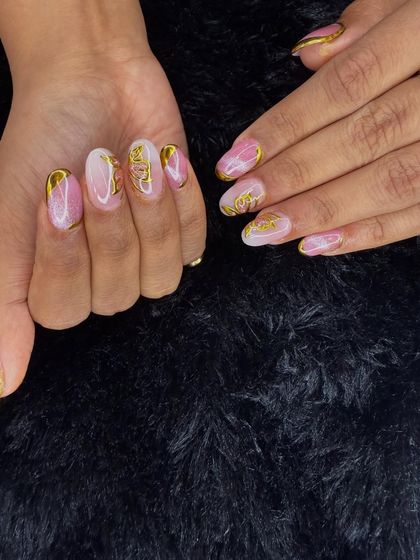 A glamorous set featuring a pink and gold glitter base with intricate, textured gold accents. This look is perfect for a party or special occasion.