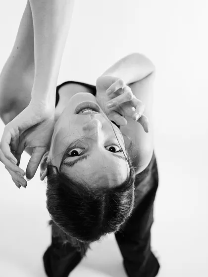 A creative and expressive black and white portrait, with the model's hands framing her upside-down face, creating a surreal and captivating image.