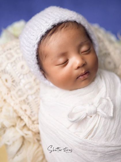 This portrait showcases a simple white wrap with a bow detail and a matching white bonnet for a clean, classic look.