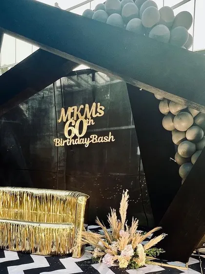 A closer look at the 60th birthday stage, showing the gold fringe sofa and pampas grass arrangements.