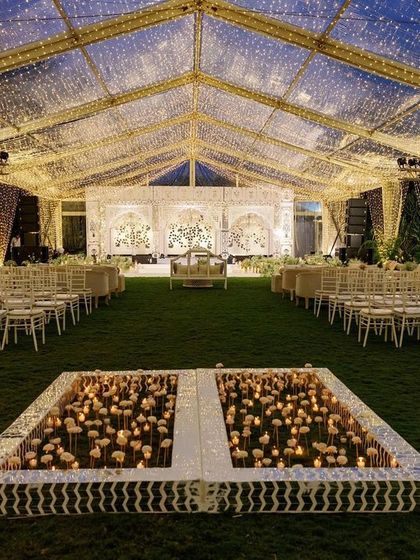 The sangeet stage viewed from the entrance, with the candle-lit dance floor in the foreground. This perspective highlights the grandeur and thoughtful layout of the entire event space.