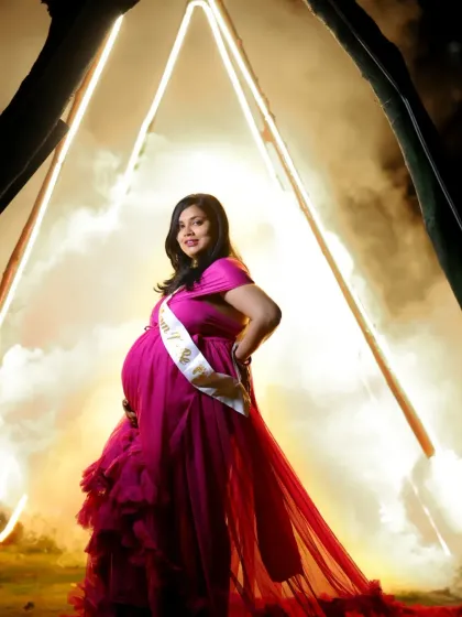 A creative outdoor night shot with a mother-to-be in a pink gown, framed by glowing neon lights and smoke for a truly unique and modern maternity photo.