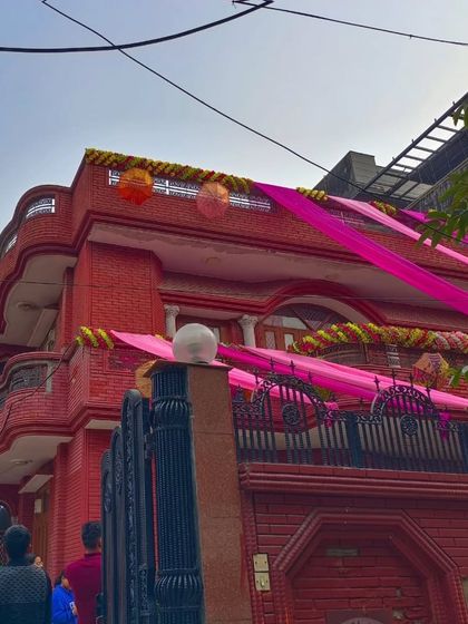 A full view of a beautiful red brick house decorated with bright pink drapes and hanging ornaments. The decor adds a festive touch while complementing the house's color.