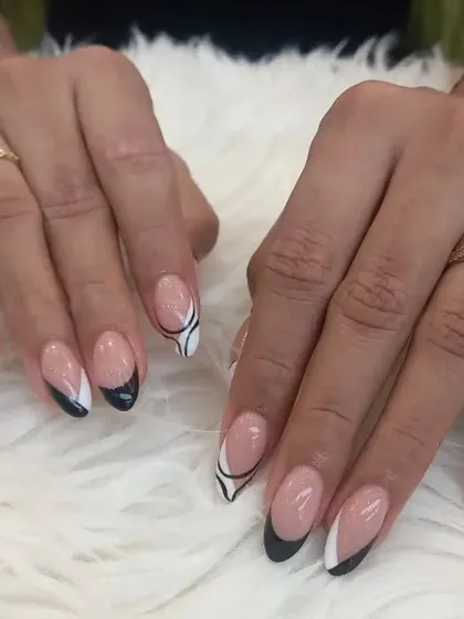 This artistic French manicure combines black and white tips with abstract swirl designs on an almond-shaped nail. It's a creative and stylish reinterpretation of a classic look.