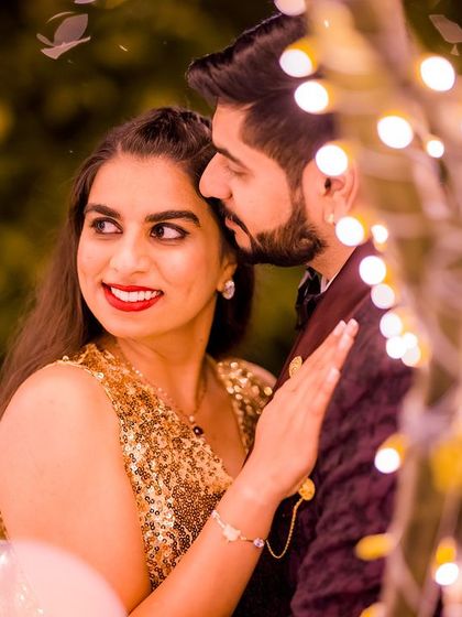 A close-up, intimate moment between the glamorous couple, with the bokeh lights creating a magical effect.
