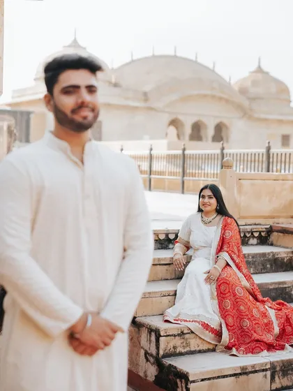 A portrait using shallow depth of field to create a dynamic between the couple, with the bride seated elegantly in the background.