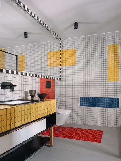 This bathroom in Cocoon House is a playful exploration of the De Stijl art movement, using a grid of white tiles as a canvas. We introduced bold blocks of primary colors like yellow, red, and blue to create a vibrant, graphic, and entirely unique washroom experience.