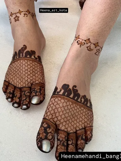 An adorable feet design for a baby shower. The main part of the foot has a traditional net pattern with an elephant border, while the ankle features a delicate chain of baby-themed charms.