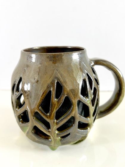 Another angle of the double-walled leaf mug, showcasing how the light catches the intricate carvings. Each one is unique, with slight variations that make it truly one of a kind.