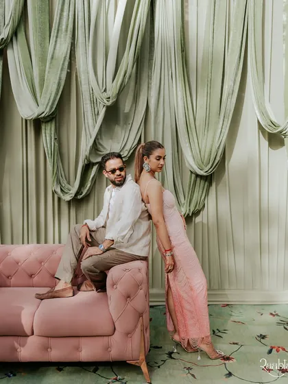 A stylish portrait of the couple posing on a pink sofa, exuding cool confidence and modern elegance.