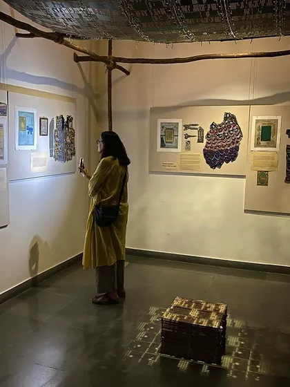 Pushpamala N examining the archival materials on the wall.
