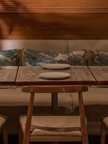 A close-up of the table setting at Biergarten. The combination of a stone tabletop, simple wooden chairs, and soft upholstered seating reflects our focus on natural, high-quality materials.