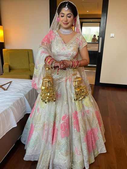 A gorgeous bride in a unique white and pink lehenga. I styled her hair in a classic updo with a pink rose to match.