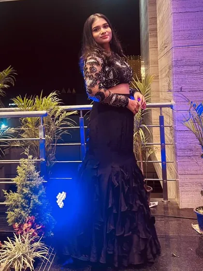 A full-length view of a client in a modern black ensemble. I designed this look with a sheer, embroidered long-sleeve crop top and a tiered ruffle skirt for a chic, contemporary vibe.