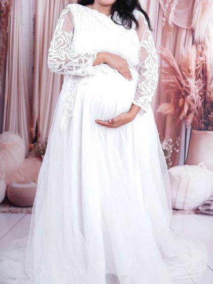 Look like a dream in this all-white maternity gown. The dress has intricate lacework on the sleeves and is made from a soft net fabric, perfect for creating pure and angelic photos.