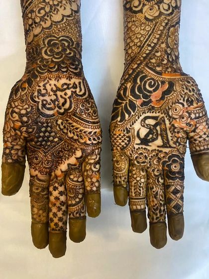 A close-up of the palms for bride Sunera. You can see the groom's initial 'A' on one hand and her name beautifully written on the other.