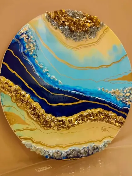 Adding a pop of color to your home decor with vibrant resin artwork. This abstract geode wall art in shades of blue, yellow, and gold makes a stunning statement piece for any room.